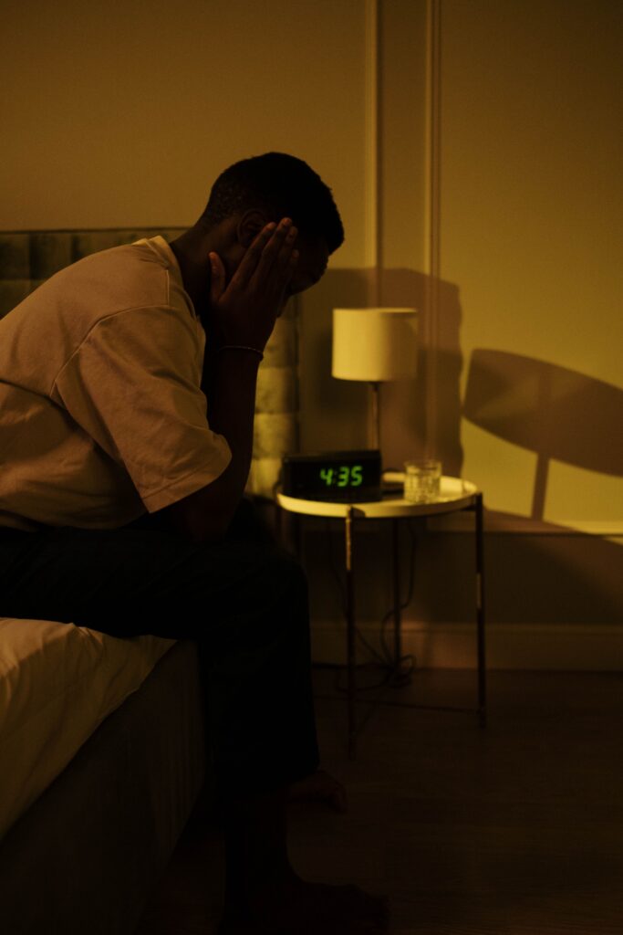 Sportif assis sur son lit la nuit, incapable de dormir la veille d'une compétition.