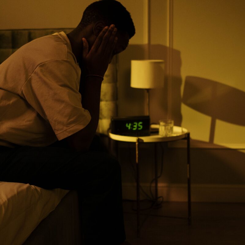 Sportif assis sur son lit la nuit, incapable de dormir la veille d'une compétition.